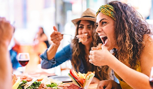 Friends smiling while enjoying meal at restaurant