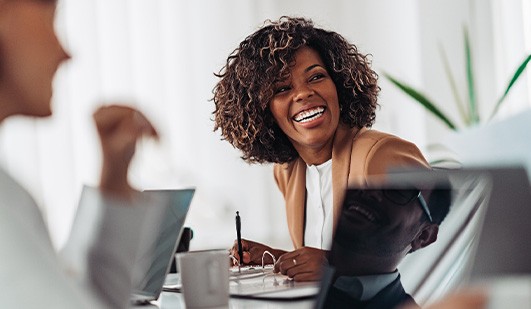 Woman smiling while taking notes during meeting