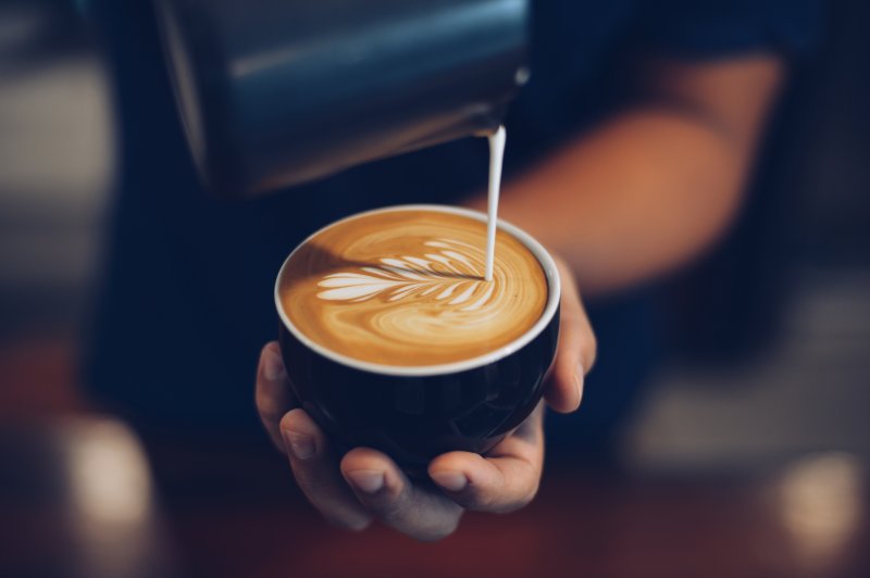 Someone pouring creamer into a cup of coffee